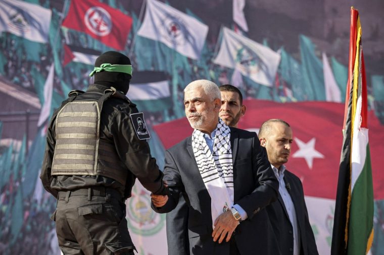 Yahya al-Sinwar (C), Gaza Strip chief of the Palestinian Islamist Hamas movement, shakes hands with a masked fighter of Hamas' Qassam Brigades during a rally marking the 35th anniversary of the group's foundation, in Gaza City on December 14, 2022. Hamas will end talks on securing a prisoner exchange with Israel unless there is progress soon, the militant group's leader in the Gaza Strip said on December 14. Since Israel's 2014 invasion of the Gaza Strip, the Islamist group has held the bodies of Israeli soldiers Oron Shaul and Hadar Goldin, although Hamas has never confirmed their deaths. Earlier this year Hamas published a video of an Israeli civilian detained for seven years in the enclave. (Photo by MOHAMMED ABED / AFP) (Photo by MOHAMMED ABED/AFP via Getty Images)