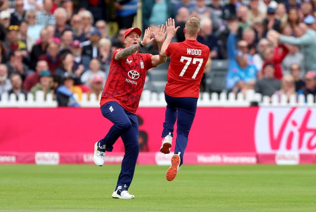 Englandâs Luke Wood, right, leaps to high-five Brydon Carse after taking the wicket of the West Indiesâ Evin Lewis from the first ball of the match