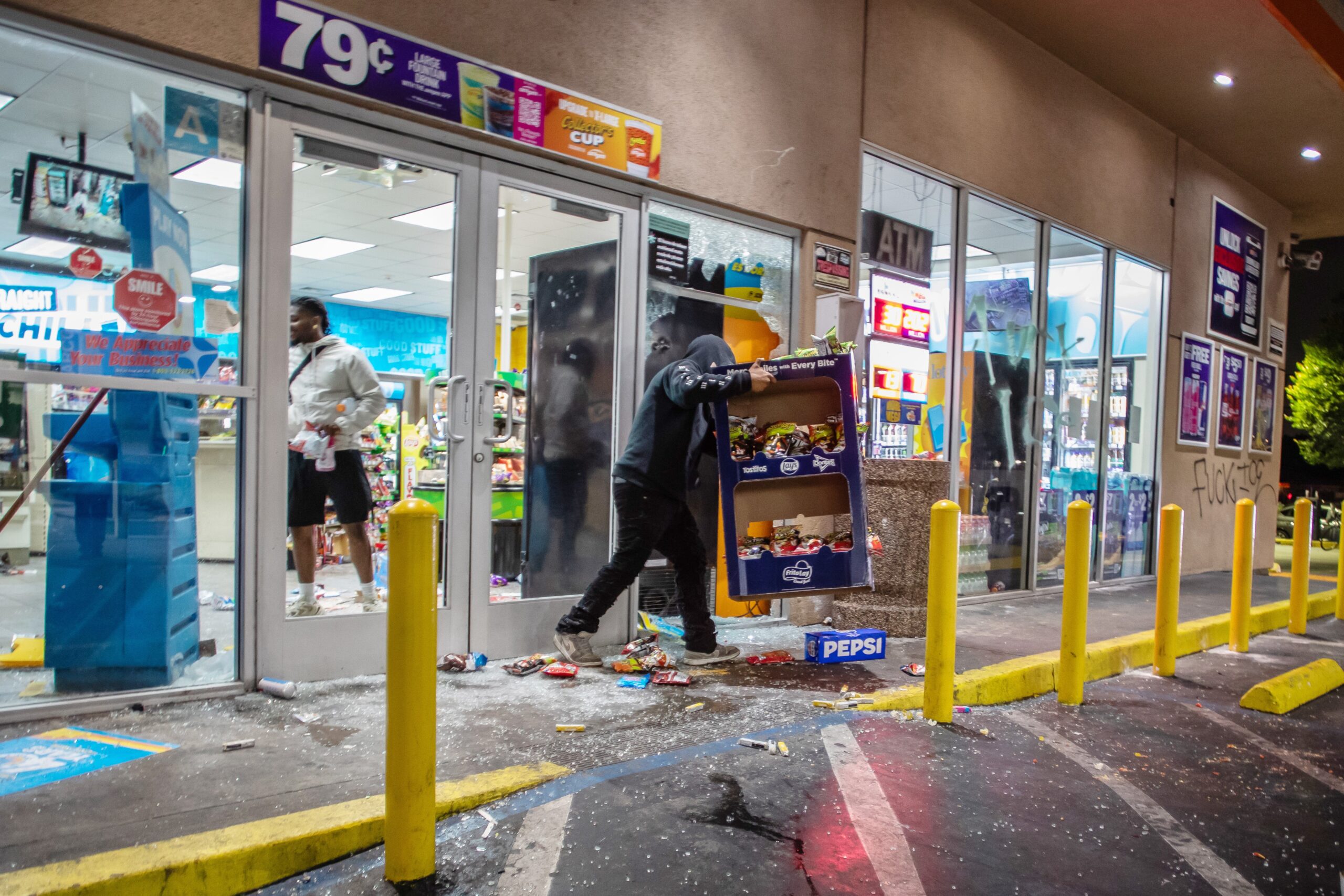 Protesters loot a gas station store during immigration protests on in Paramount on Saturday