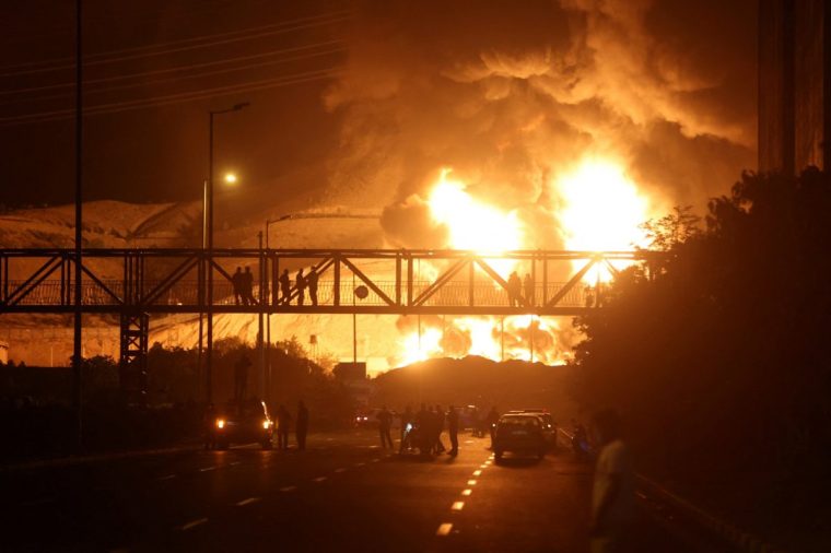 People watch from a bridge as flames from an Israeli attack rise from Sharan Oil depot, following Israeli strikes on Iran, in Tehran, Iran, June 15, 2025. Majid Asgaripour/WANA (West Asia News Agency) via REUTERS ATTENTION EDITORS - THIS PICTURE WAS PROVIDED BY A THIRD PARTY