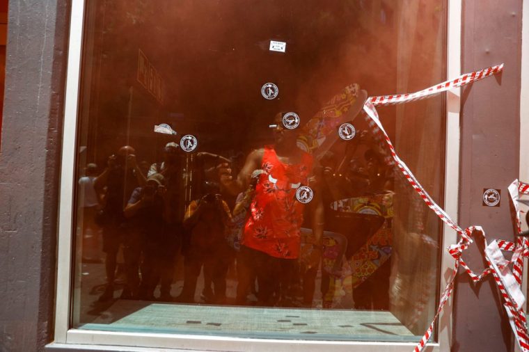 A tourist uses his phone inside the hotel as demonstrators shoot water pistols during a protest against mass tourism, in Barcelona, Spain June 15, 2025. REUTERS/Bruna Casas