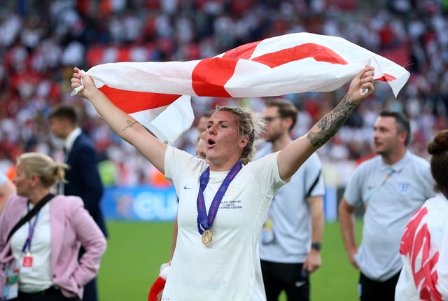 Millie Bright holding an England flag in the air