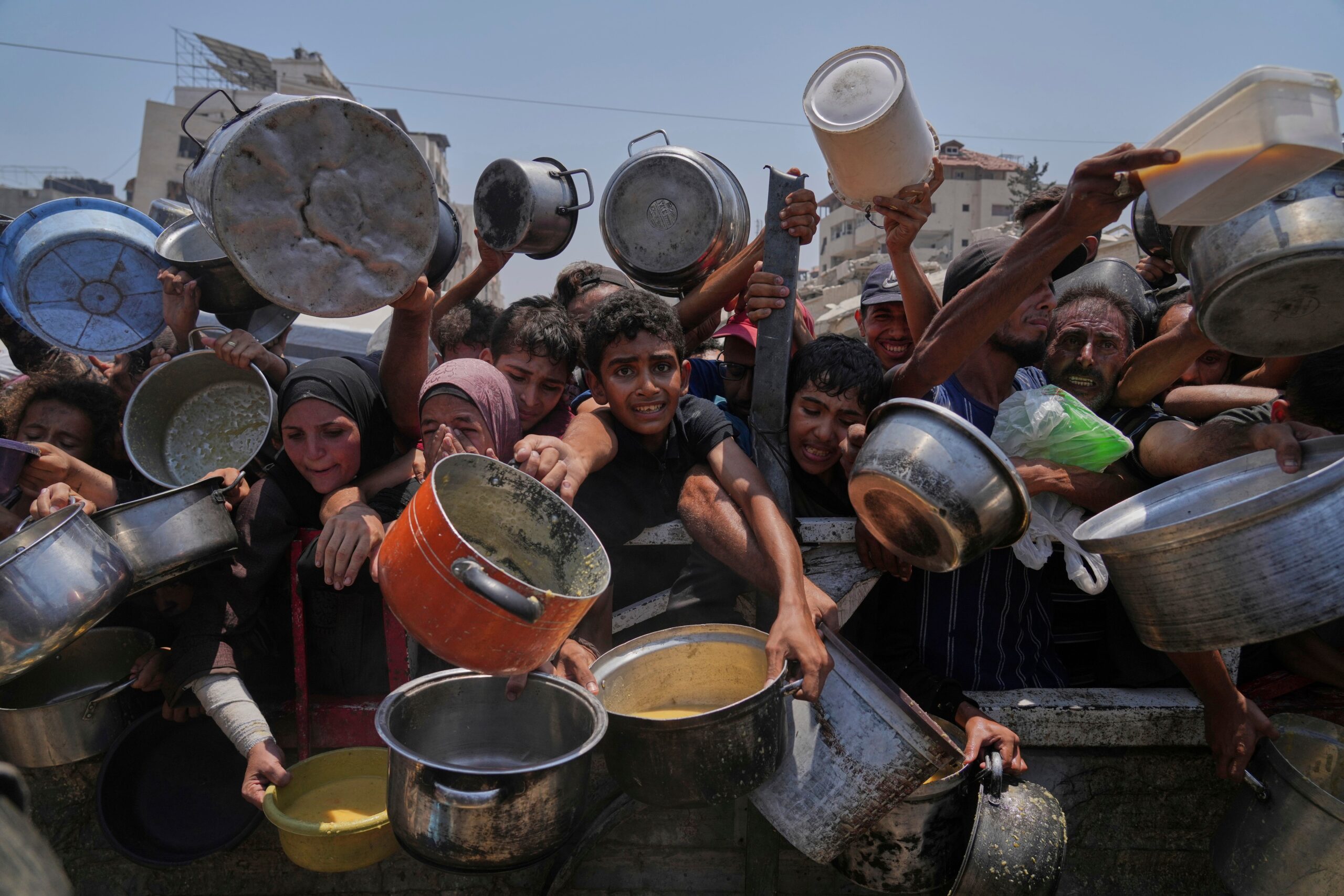 Palestinians struggle to get donated food at a community kitchen, in Gaza City