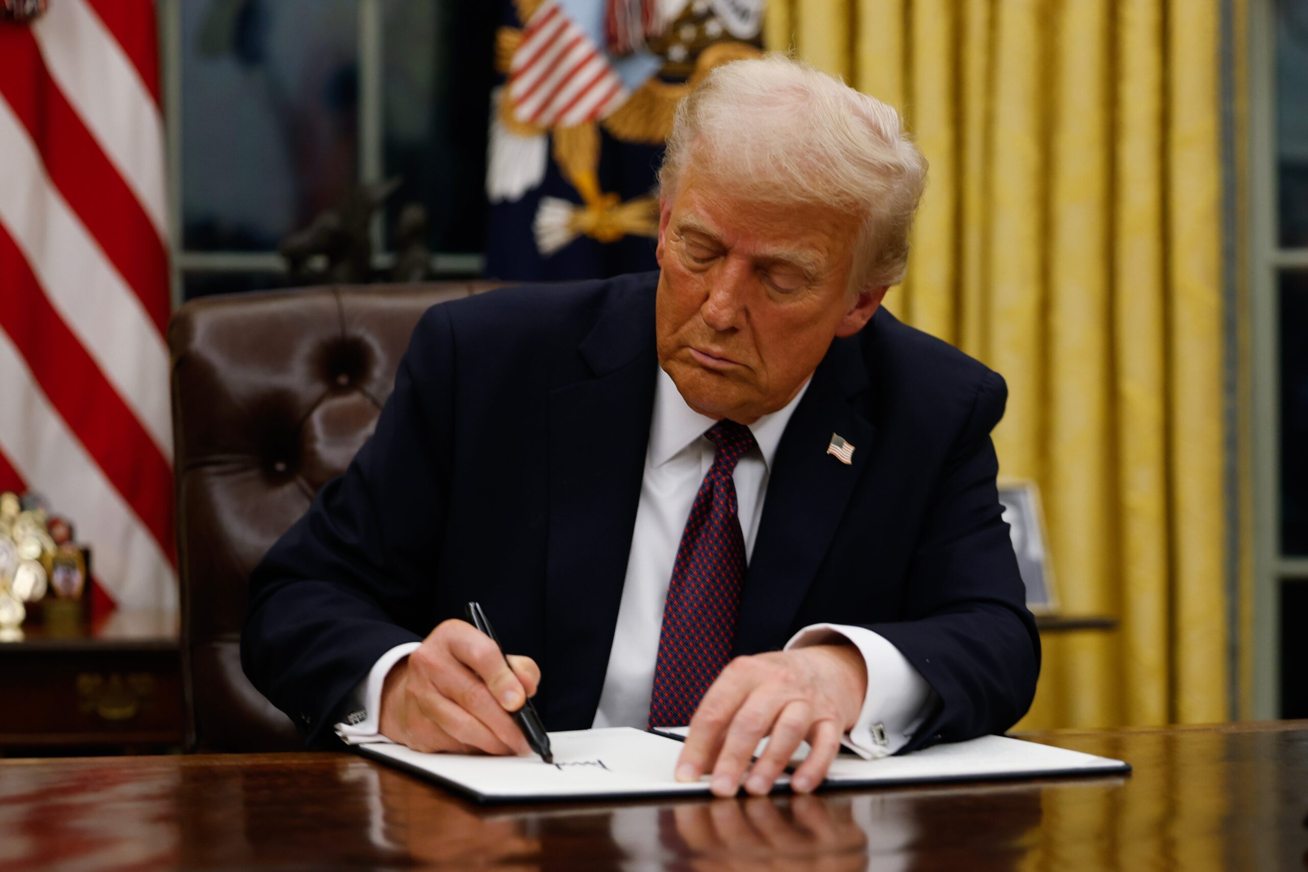 President Donald Trump signing an executive order in the Oval Office
