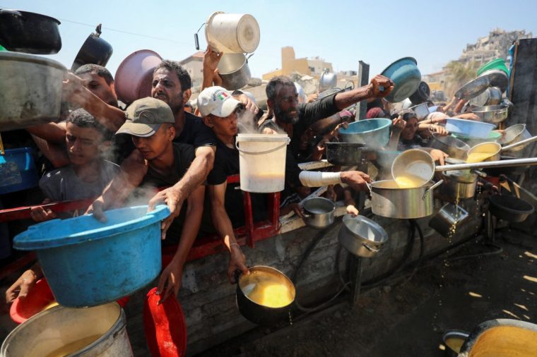 Palestinians gather to receive food from a charity kitchen, amid a hunger crisis, in Gaza City, July 23, 2025. REUTERS/Mahmoud Issa