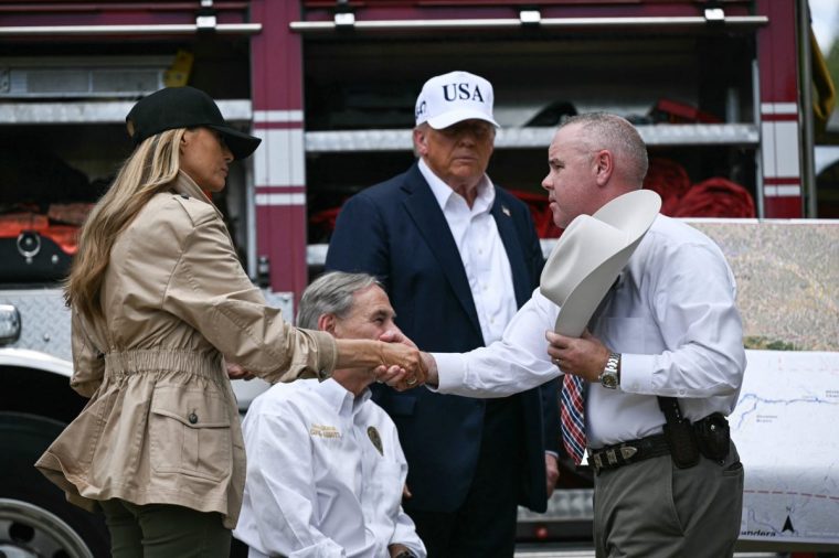 US President Donald Trump, Texas Governor Greg Abbott (2L), and First Lady Melania Trump (L) meet with local officials and first responders near the Guadalupe River following devastating flooding that ocurred in the area over the July 4 weekend, in Kerrville, Texas, on July 11, 2025. At least 120 people are dead and more than 170 still missing, following July 4 holiday weekend floods that ravaged the central Texas Hill Country -- including a river bank cluttered with children's summer camp cabins. (Photo by Brendan SMIALOWSKI / AFP) (Photo by BRENDAN SMIALOWSKI/AFP via Getty Images)