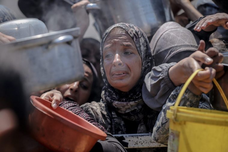 GAZA CITY, GAZA - JULY 25: Palestinians gather in long queues under scorching heat to receive food distributed by a charity organization in the Rimal neighborhood of Gaza City, Gaza on July 25, 2025. Ongoing Israeli attacks and a worsening humanitarian crisis have led to severe food shortages, forcing hundreds to wait for hours to secure a single meal. (Photo by Saeed M. M. T. Jaras/Anadolu via Getty Images)