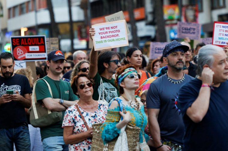 Demonstrators hold placards during a protest against mass tourism in Alicante, Spain, July 25, 2025. REUTERS/Eva Manez