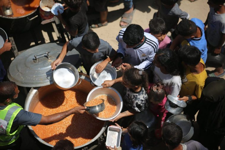 DEIR AL-BALAH, GAZA - JULY 29: Palestinians carrying pots and containers gather as a charity distributes food in Az-Zawayda, Deir al-Balah, Gaza, where access to food remains difficult due to Israel's ongoing blockade and attacks, on July 29, 2025. (Photo by Hassan Jedi/Anadolu via Getty Images)