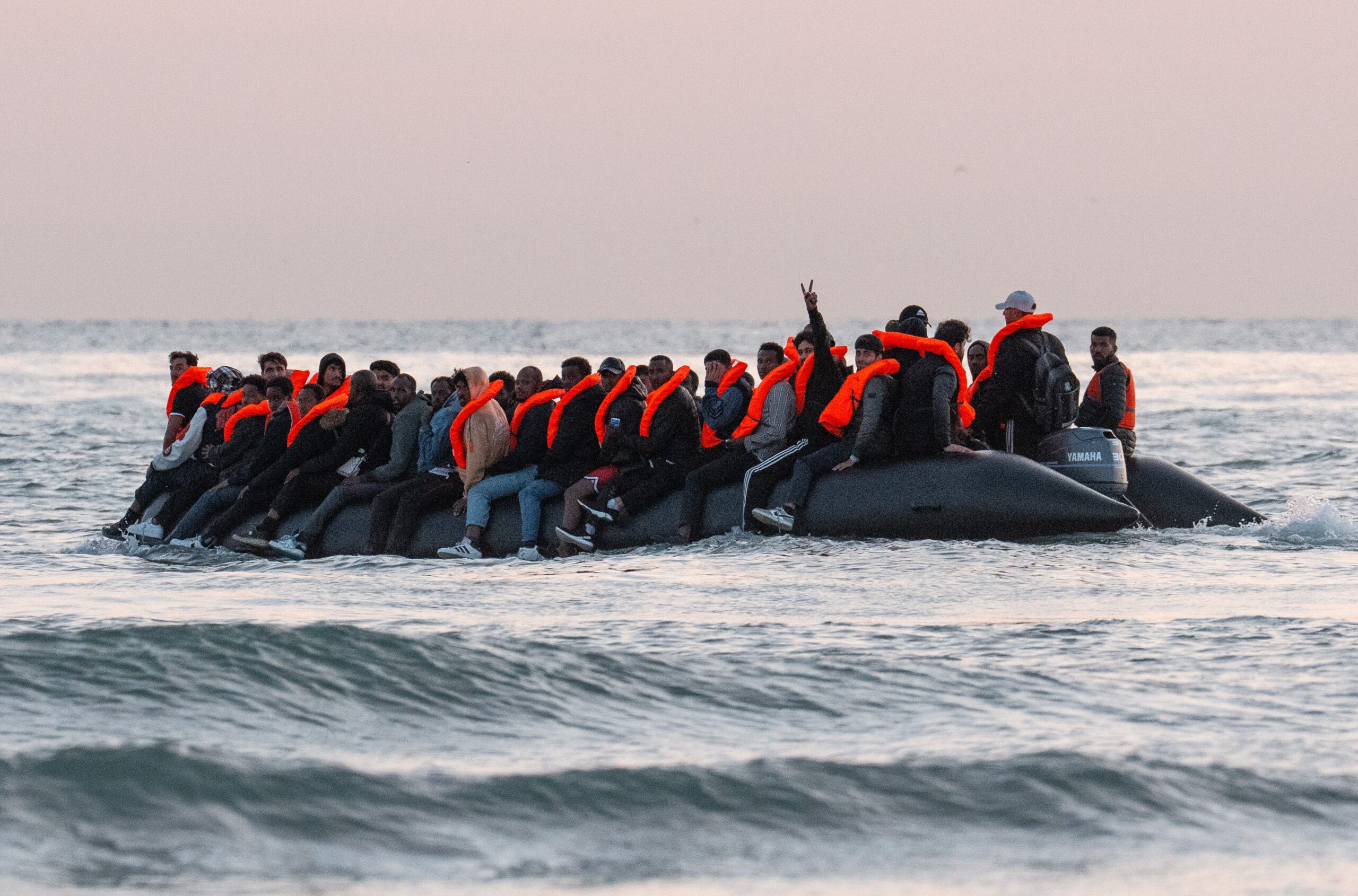 A man gestures from a dinghy as migrants prepare to sail into the English Channel on July 10, 2025 in Gravelines, France.
