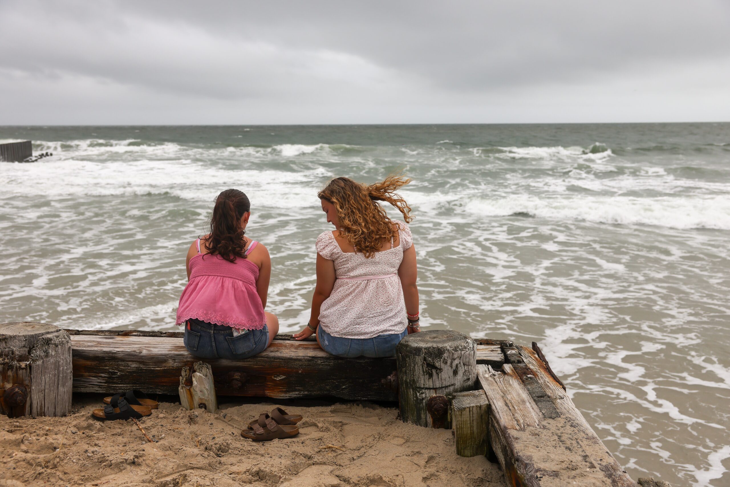 Two teens gaze out to sea, enjoying the oceanic drama