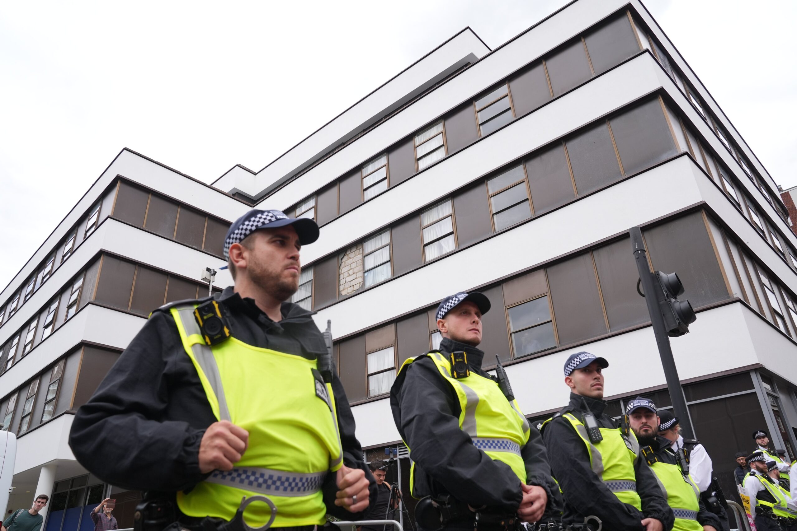 Police officers observe two groups of protesters outside the Thistle City Barbican Hotel in central London