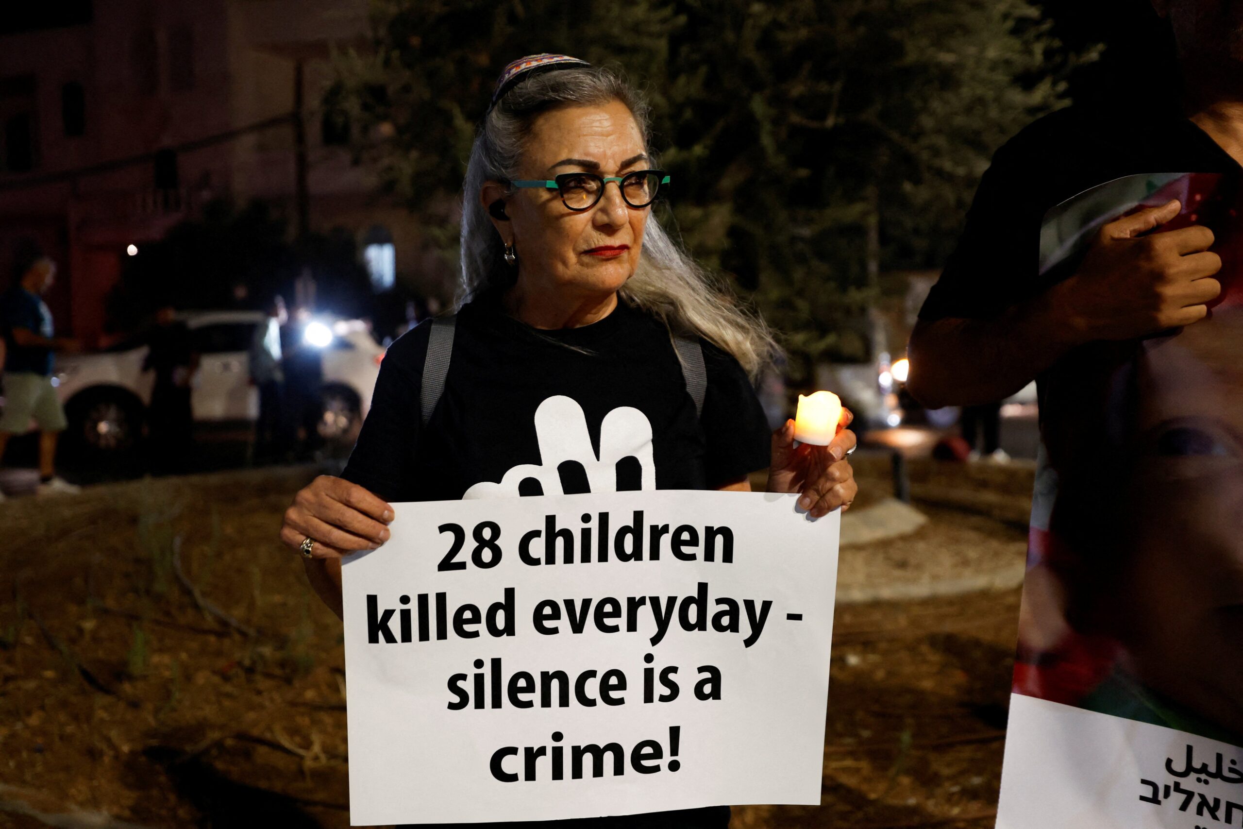 A Jewish rabbi holds a signs as Palestinian and Israeli activists take part in a protest against starvation in Gaza, near Beit Jaa