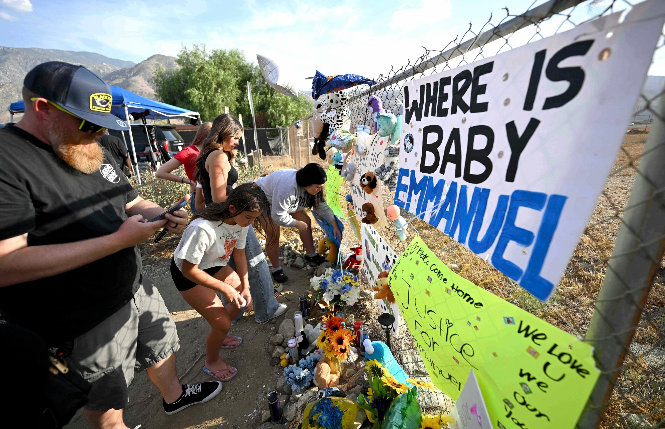 Visitors gather around a makeshift memorial prior to a vigil for missing 7-month-old Emmanuel Haro outside the child's home
