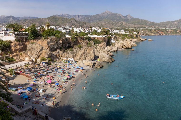 Fishermen in typical fishing boat leaving Calahonda beach crowded with beachgoers. Nerja, Costa del Sol, Malaga Province, Andalusia, southern Spain. (Photo by: Ken Welsh/UCG/Universal Images Group via Getty Images)