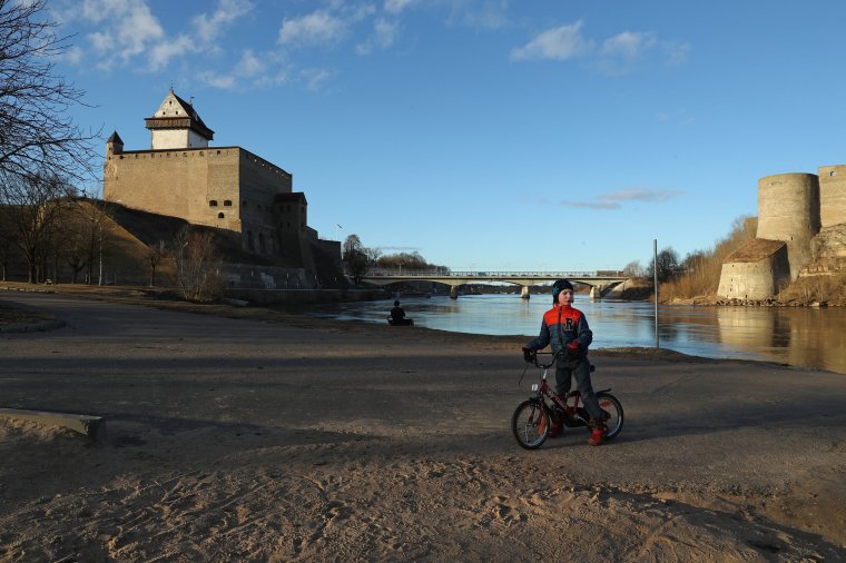 NARVA, ESTONIA - MARCH 23: A Russian-speaking boy pauses while riding his bike along a promenade along the Narva River below Hermann Castle (L) and opposite Ivangorod Fortress, which is on the Russian side the Narva River, on March 23, 2017 in Narva, Estonia. Estonia is a member of the European Union and shares its eastern border with Russia. Russians make up about a quarter of the Estonian population and Estonia has largely succeeded in integrating its Russian minority and stemming any militant pro-Russian movement. Hermann Castle, originally built by Danes in 1256, was for centuries an outpost of the German Teutonic Knights. (Photo by Sean Gallup/Getty Images)
