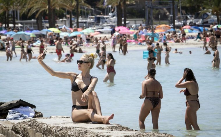 A tourist takes a selfie at Palma's Beach in Palma de Mallorca on July 18, 2025. (Photo by JAIME REINA / AFP) (Photo by JAIME REINA/AFP via Getty Images)