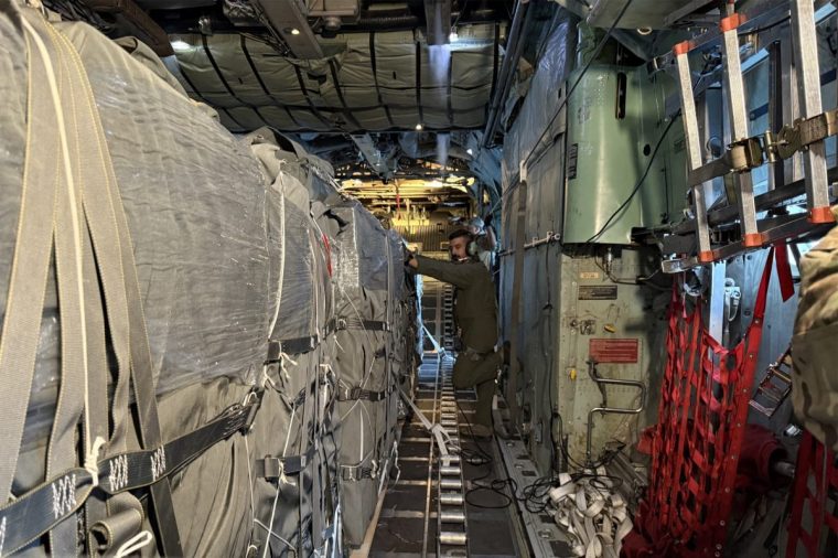 An airman stands next to a shipment of humanitarian aid packages loaded onto a C-130 Hercules military transport aircraft at King Abdullah II airbase in Zarqa on July 30, 2025 ahead of an airdrop mission over the Gaza Strip. (Photo by Ahmad SHOURA / AFP) (Photo by AHMAD SHOURA/AFP via Getty Images)