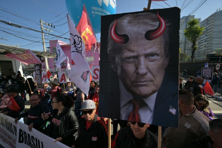 An activist holds a poster depicting US President Donald Trump bearing devil horns during a protest in defence of national sovereignty following the US government trade taxes and sanctions on Brazil, near the US consulate, in Sao Paulo, Brazil, on August 1, 2025. President Donald Trump ordered massive tariffs on Brazil on July 30, 2025, and sanctions against the judge overseeing a trial of his far-right ally Jair Bolsonaro, who is accused of attempting a coup in Latin America's biggest economy. (Photo by NELSON ALMEIDA / AFP) (Photo by NELSON ALMEIDA/AFP via Getty Images)