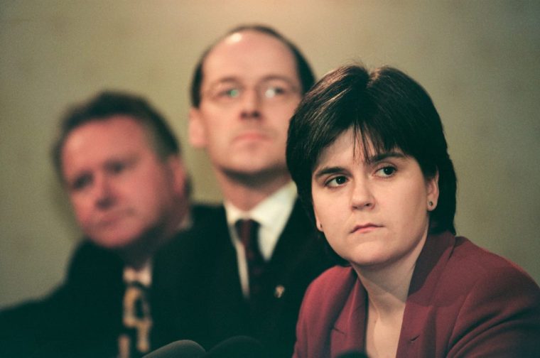 The Scottish National Party's Nicola Sturgeon (right) listening to her party leader Alex Salmond addressing the media at the launch of the SNP's 1999 manifesto for the Holyrood election campaign in Edinburgh, Scotland. Ms Sturgeon was elected to the newly-created Scottish parliament in 1999 and went on to serve as the country's Deputy First Minister under Alex Salmond MSP and then as First Minister. At the time of the 1999 election she was working as a solicitor in the Drumchapel Law and Money Advice Centre in Glasgow. (Photo by Colin McPherson/Corbis via Getty Images)