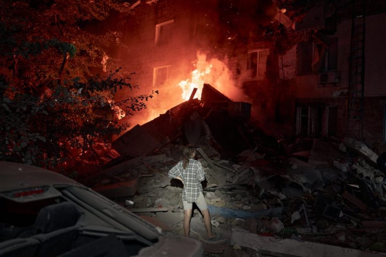 KYIV, UKRAINE - AUGUST 28: A person looks on as rescuers work at the site of a residential building hit by a Russian missile on August 28, 2025 in Kyiv, Ukraine. The strike struck between the third and fourth floors of a five-story house, according to Interior Minister Ihor Klymenko. At least four people were reported killed, with 20 injured, as emergency services continued operations. (Photo by Kostiantyn Liberov/Libkos/Getty Images)
