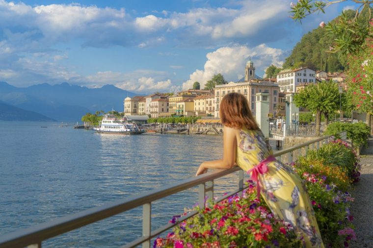 Woman admiring sunset over Lake Como and Bellagio old town, Como province, Lombardy, Italy