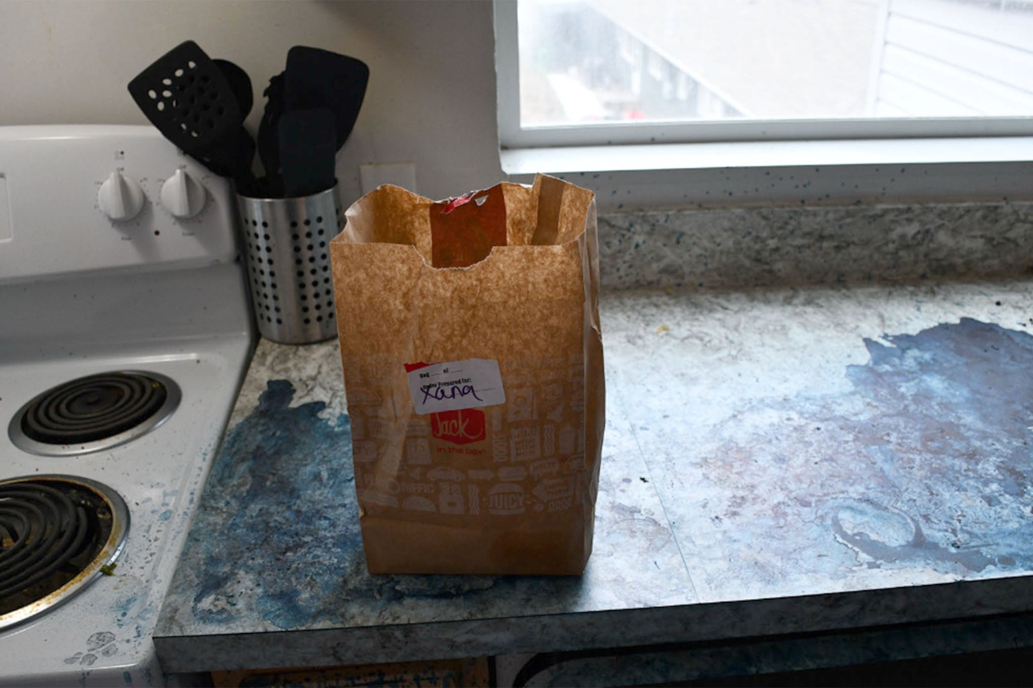 Xanaâs half-eaten DoorDash order sits in a crumpled paper bag on the counter in the kitchen
