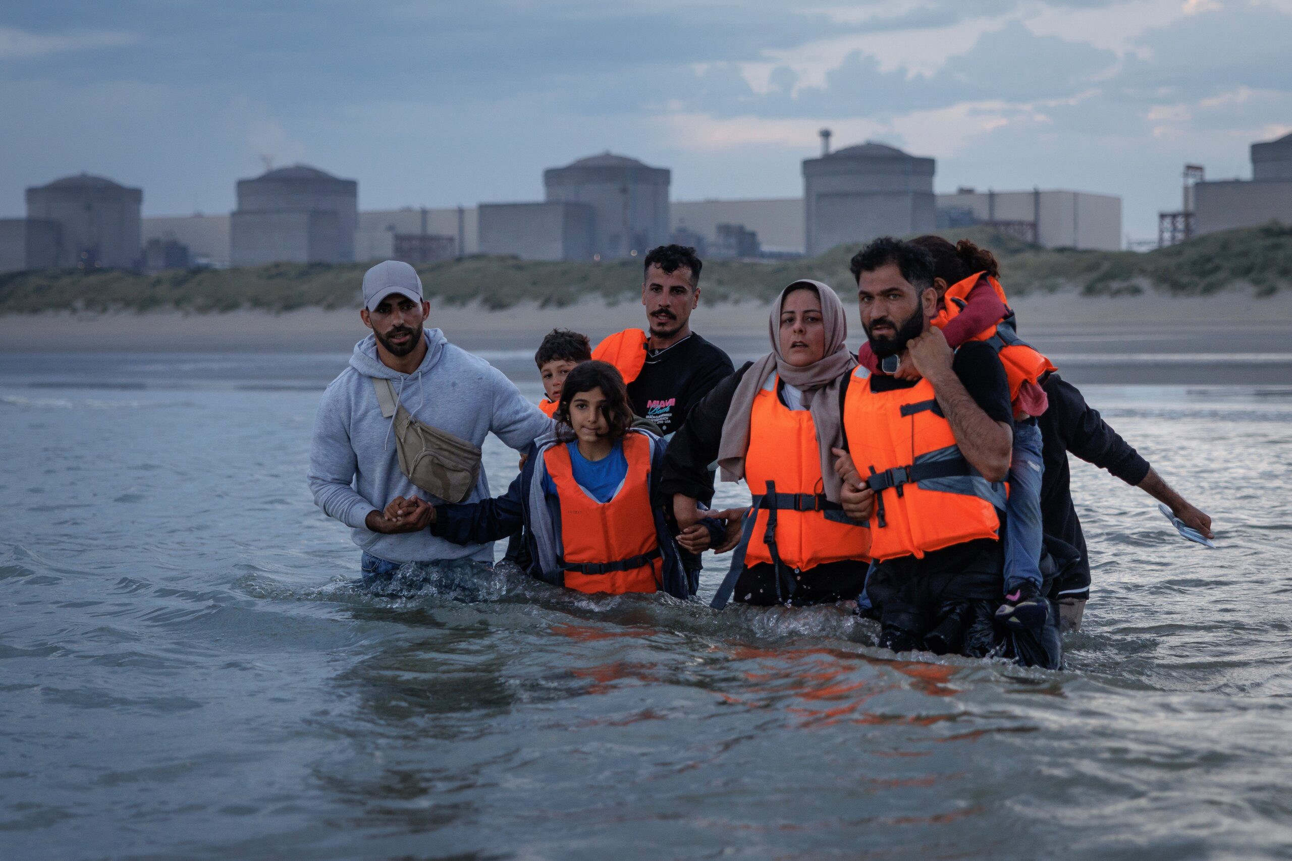Migrant families wade into the sea in an attempt to board a small boat on August 12.