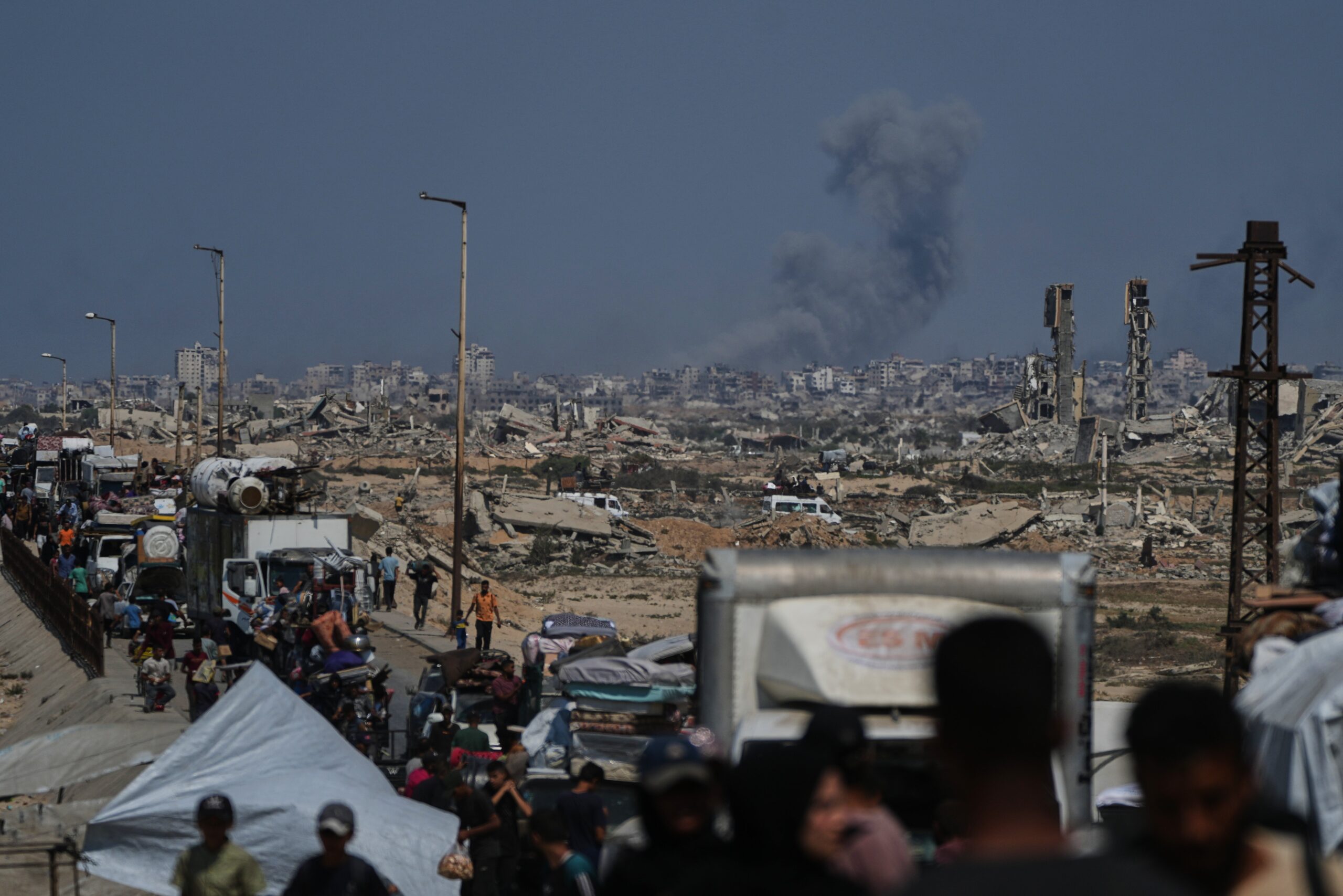 Smoke billows over Gaza City following an Israeli airstrike as displaced Palestinians flee on 24 Sept 2025