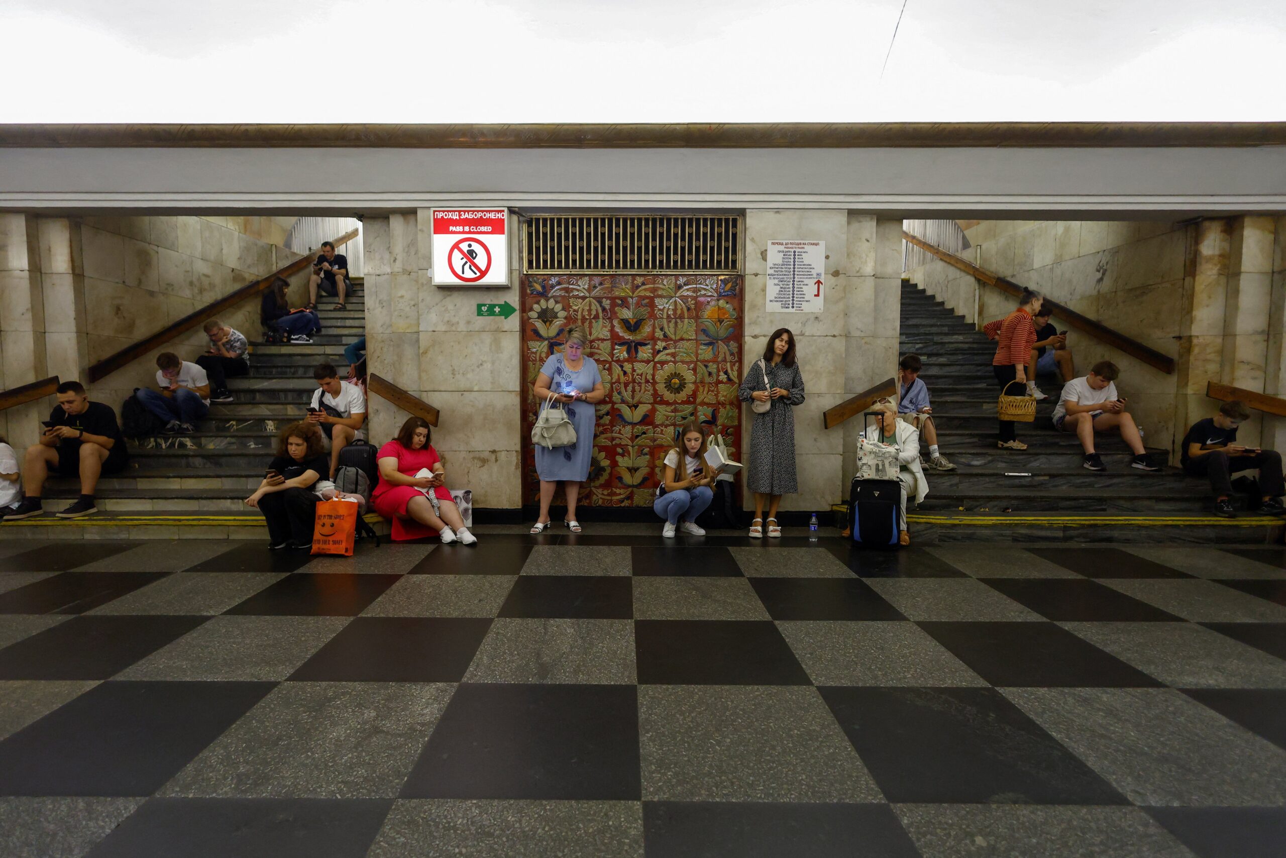 People take shelter inside a metro station while Russian strike drones fly over Kyiv
