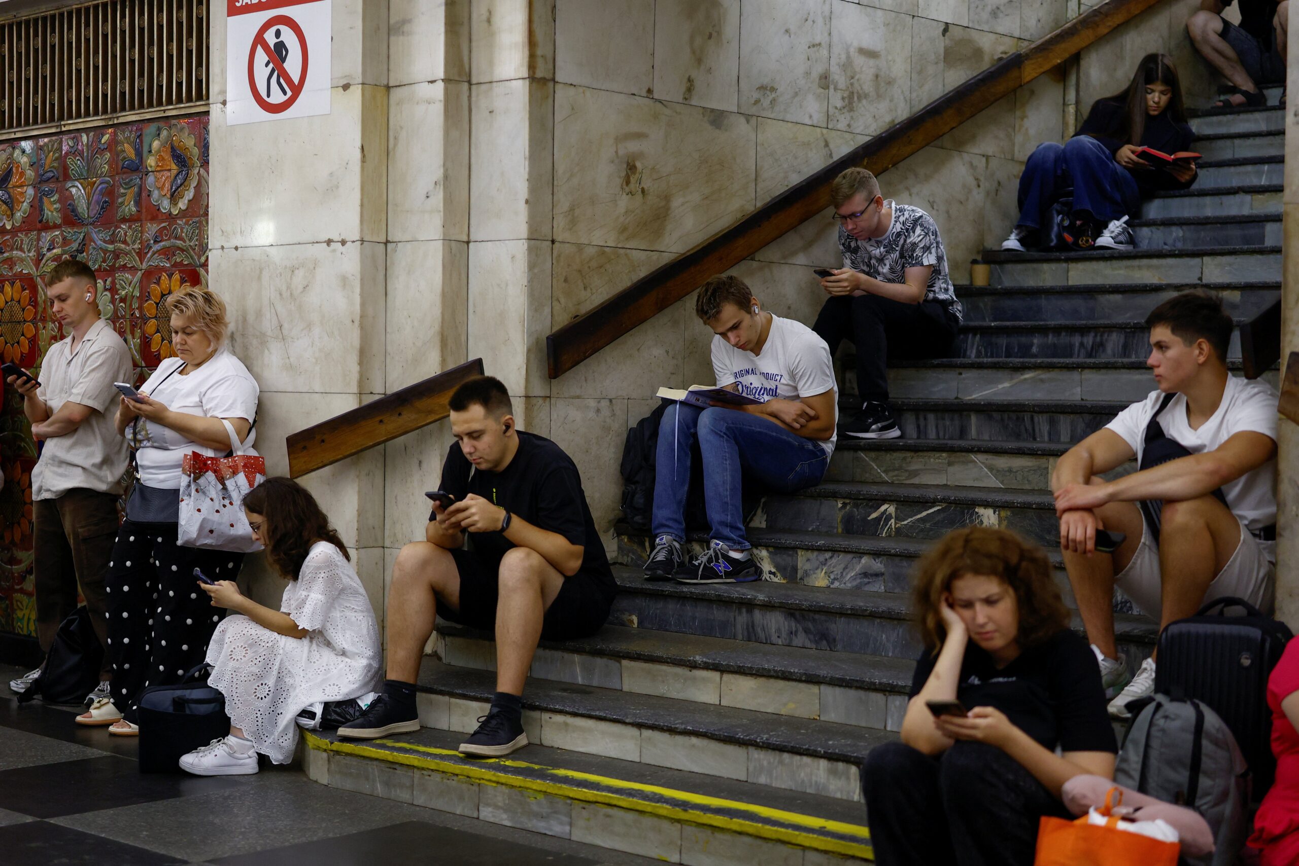 People take shelter inside a metro station while Russian strike drones fly over Kyiv