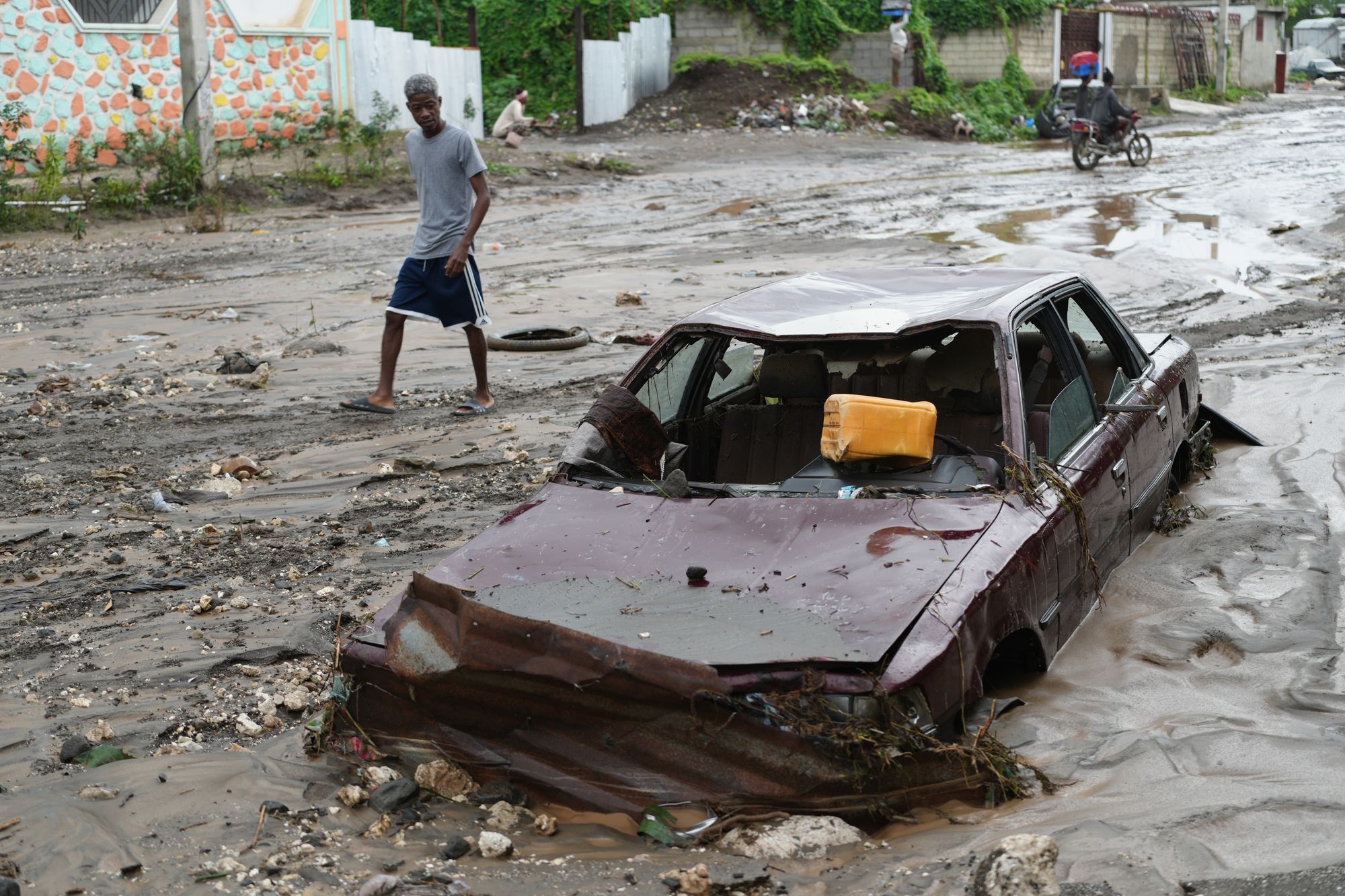 Residents wade through a flooded stream in the aftermath of Hurricane Melissa in Petit-Goave, Haiti on Thursday