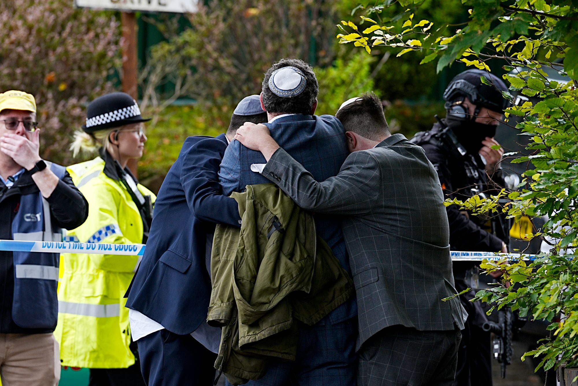 Members of the Jewish community comfort each other near to the Heaton Park Hebrew Congregation synagogue in Crumpsall, Manchester