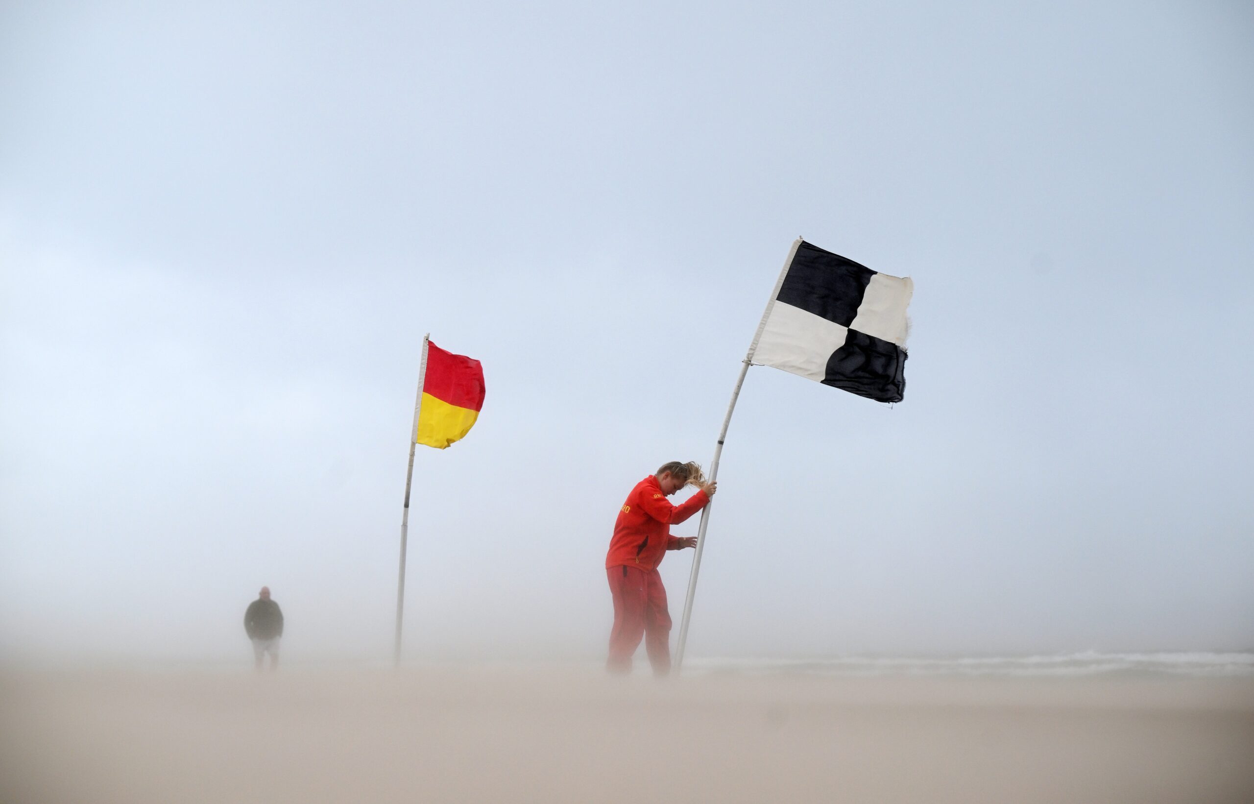 An RNLI lifeguard battles with a flag amid winds in Northern Ireland