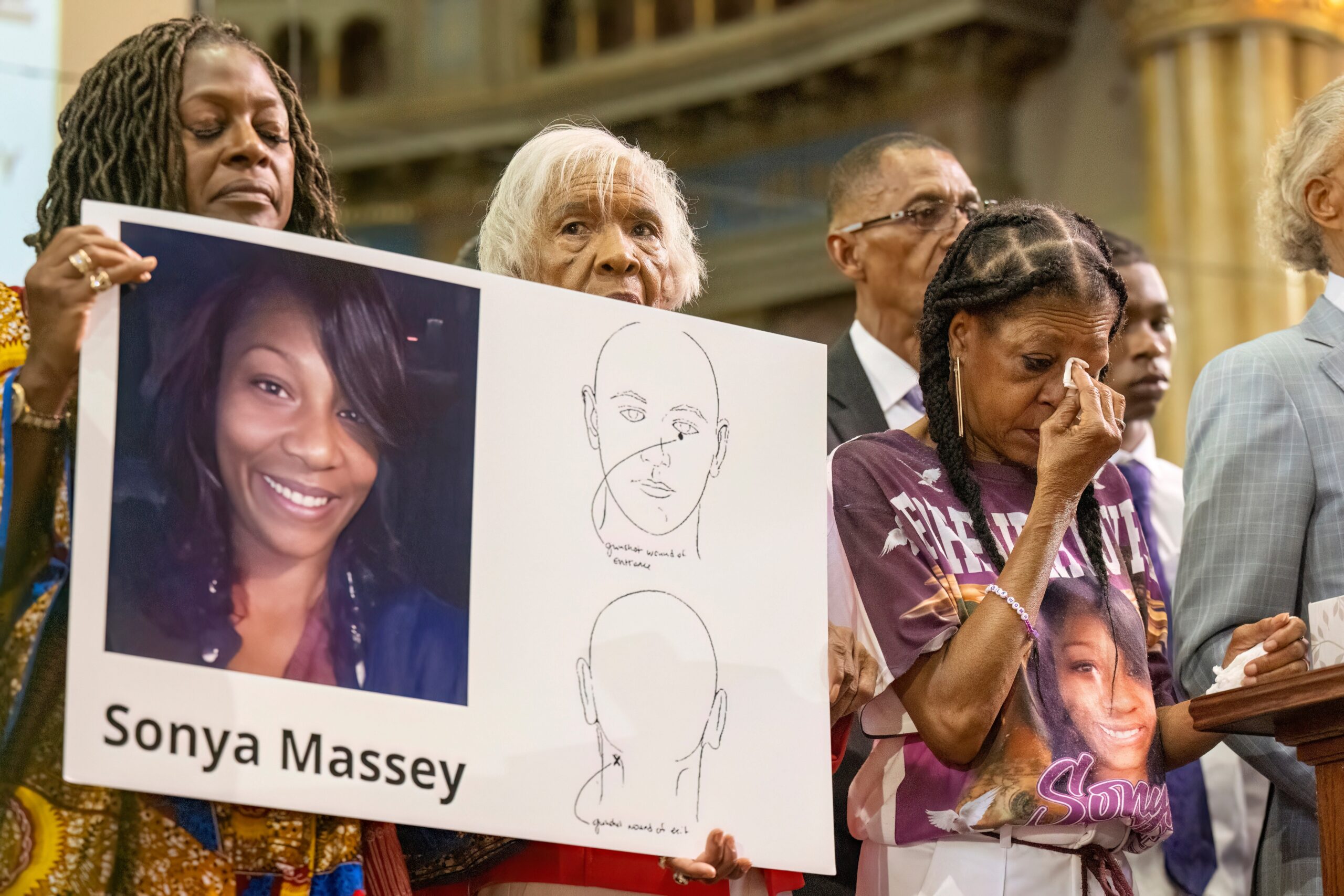 Sonya Massey's family members hold a poster with her photo and a diagram from her autopsy report. Massey was killed in her home on July 6, 2024, by a Sangamon County Sheriff's Deputy