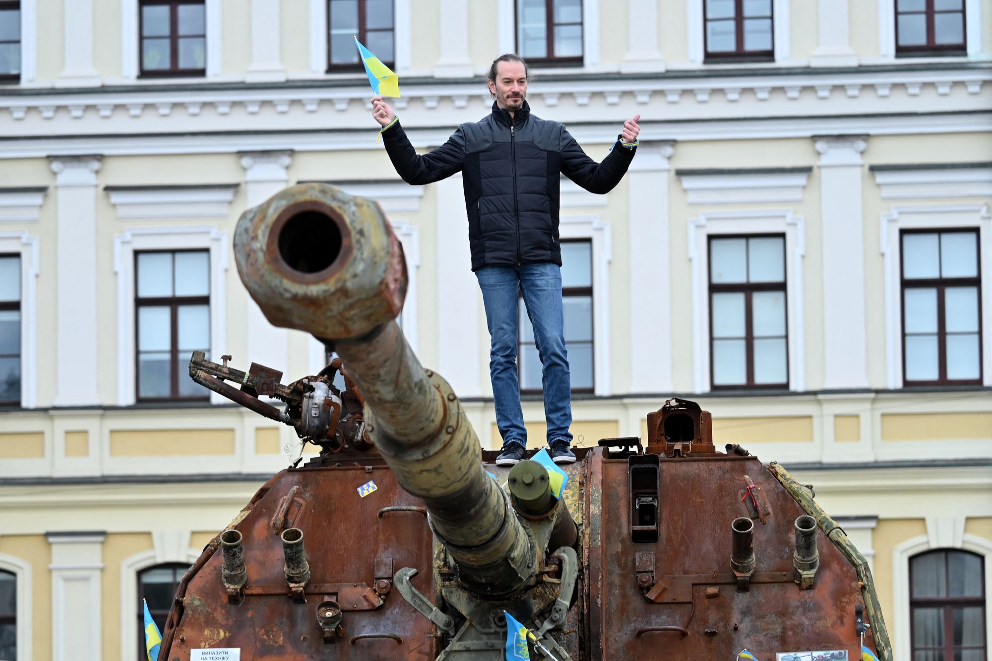 A man holding Ukraine's flag on a Russian self-propelled gun at an open-air exhibition of destroyed Russian equipment in Kyiv