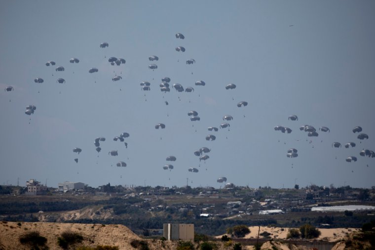 SOUTHERN ISRAEL, ISRAEL - MARCH 25: Humanitarian aid falls through the sky toward the Gaza Strip as seen from a position on the Israeli side of the border on March 25, 2024 in Southern Israel, Israel. Foreign mediators in the ongoing Israel-Hamas ceasefire negotiations have expressed cautious optimism about the talks, but a breakthrough remains elusive. Israel has vowed that it will still press on with a ground invasion of Rafah, the Gaza Strip's southernmost city, even if a temporary ceasefire is agreed to. (Photo by Amir Levy/Getty Images)
