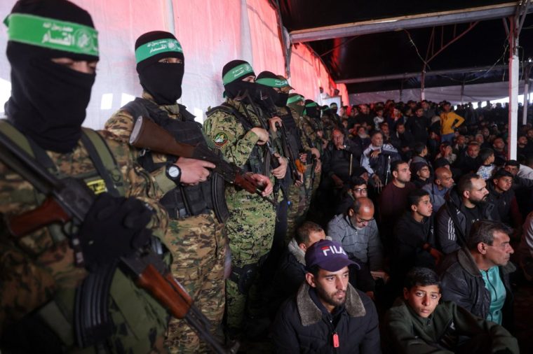 Palestinians and Hamas fighters attend a funeral ceremony for 40 militants and civilians killed during the war with Israel, at the Shati camp for Palestinian refugees north of Gaza City on February 28, 2025, amid the current ceasefire deal in the war between Israel and Hamas. Many of the remains of the deceased were reportedly found under the rubble of destroyed buildings while others were exhumed from temporary graves in order to be properly buried. (Photo by BASHAR TALEB / AFP) (Photo by BASHAR TALEB/AFP via Getty Images)