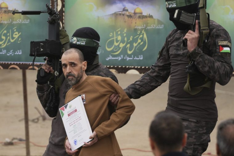 Israeli captive Eli Sharabi, who had been held hostage by Hamas in Gaza since Oct. 7, 2023, is escorted by Hamas fighters before being handed over to the Red Cross in Deir al-Balah, central Gaza Strip, Feb. 8, 2025. (AP Photo/Abdel Kareem Hana)