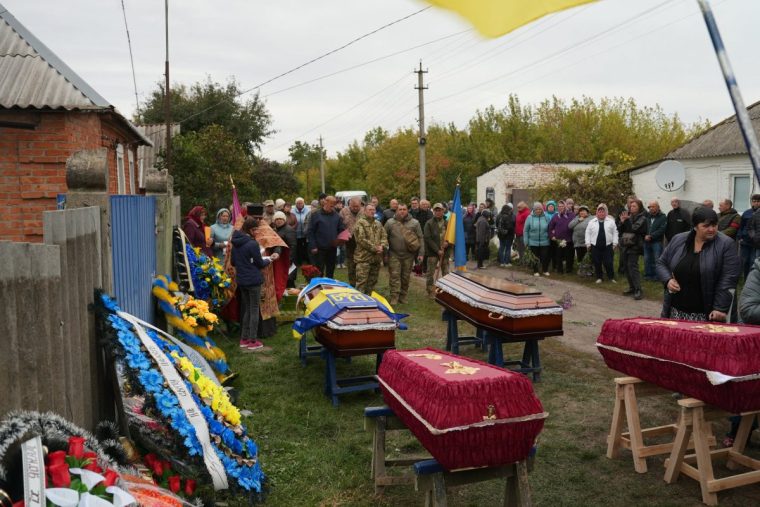 Relatives and friends mourn over coffins during a funeral ceremony for 26-year-old Alona and 35-year-old Oleksandr Lesnichenko and their children Denys and Yegor killed following a Russian drone strike in the Sumy oblast in Chernechchyna, on October 1, 2025, amid the Russian invasion of Ukraine. Russian drone strike crashed on a village in Ukraine overnight, killing two small boys and their parents, including the mother who was pregnant with twins, Ukrainian authorities said. (Photo by Yevhen Abrasimov / AFP) (Photo by YEVHEN ABRASIMOV/AFP via Getty Images)