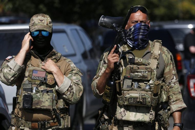 A masked US Customs and Border Protection (CBP) Border Patrol agent (L) is seen as residents of Chicago's Brighton Park neighborhood confront law enforcement at a gas station after Immigration and Customs Enforcement (ICE) agents allegedly detained an unidentified man riding in his car, in Chicago, Illinois, on October 4, 2025. US President Donald Trump, who campaigned on a pledge to deport large numbers of migrants, has encouraged authorities to be more aggressive as he seeks to hit his widely reported target of one million deportations annually. (Photo by OCTAVIO JONES / AFP) (Photo by OCTAVIO JONES/AFP via Getty Images)