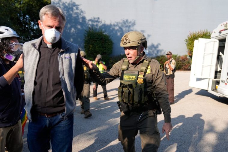 RETRANSMITTING TO REMOVE REFERENCE TO PROTESTER BEING DETAINED. HE WAS WALKING WITH HIS HANDS BEHIND HIS BACK Greg Bovino, the chief patrol agent for the U.S. Border Patrol El Centro sector, right, walks along protester with his hands behind his back near an Immigration and Customs Enforcement facility in Broadview, Ill., Friday, Oct. 3, 2025. (AP Photo/Erin Hooley)