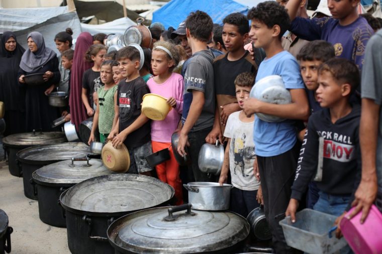 DEIR AL BALAH, GAZA - OCTOBER 13: Palestinians wait to receive hot meals distributed by charity organizations in the Nuseirat Refugee Camp, as people struggle with hunger in Deir Al Balah, Gaza on October 13, 2025. (Photo by Hassan Jedi/Anadolu via Getty Images)