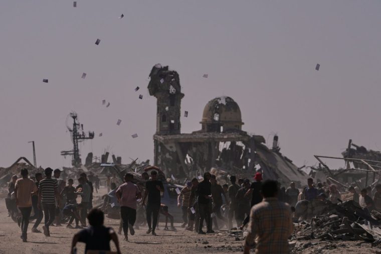 Palestinians collect leaflets dropped by an Israeli drone warning people to stay away from the so-called yellow line in Khan Younis, in the southern Gaza Strip, Monday, Oct. 20, 2025. (AP Photo/Jehad Alshrafi)