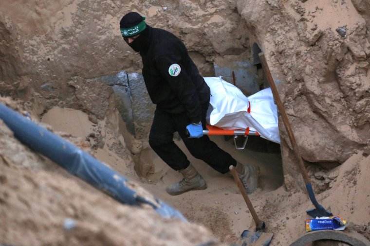 A Hamas militant carries a body retrieved from a tunnel in an area north of Khan Yunis in the southern Gaza Strip on October 28, 2025. Israel's military on October 28 accused Hamas of staging its search for the remains of a Gaza hostage body, one of 28 the group had agreed to hand over under a ceasefire deal. Hamas says it is committed to the ceasefire terms, but lacks the equipment needed to locate and excavate hostage bodies potentially buried under buildings collapsed by air strikes. (Photo by Bashar TALEB / AFP) (Photo by BASHAR TALEB/AFP via Getty Images)