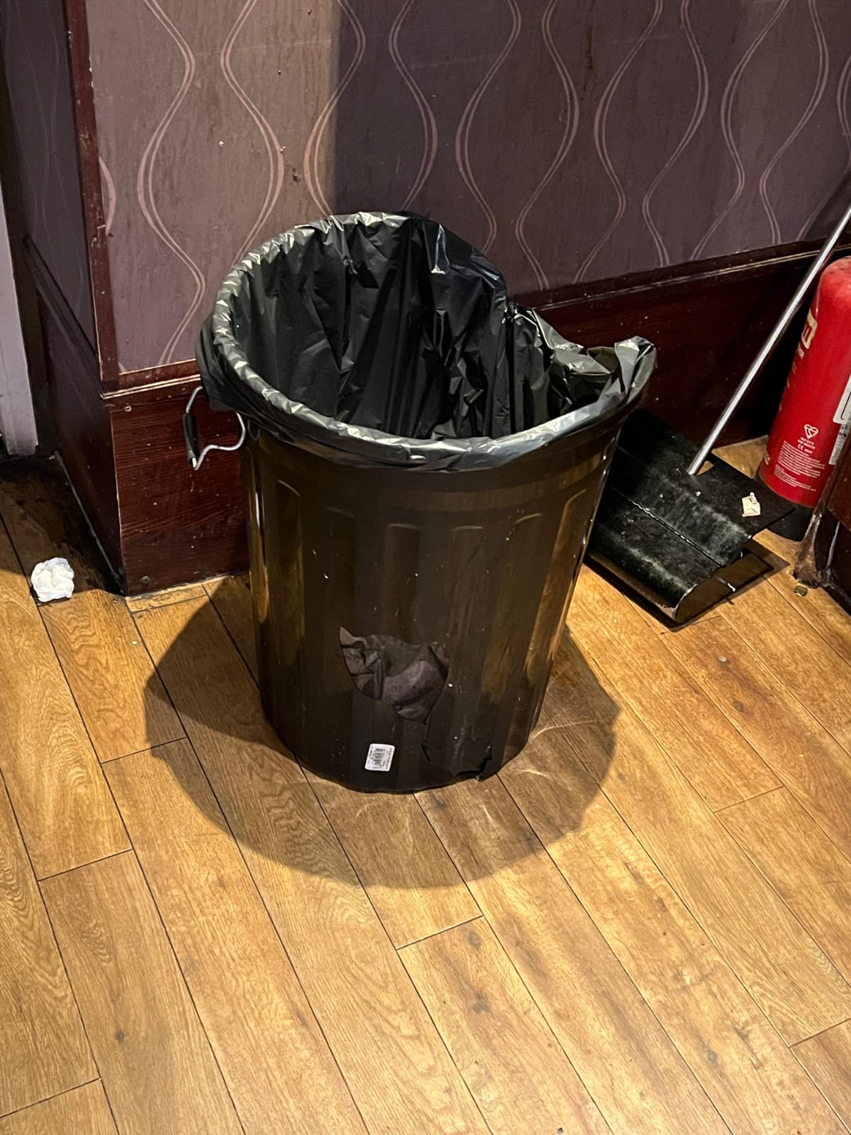 This photo depicts a broken bin with a hole in it that was located in the hotel room