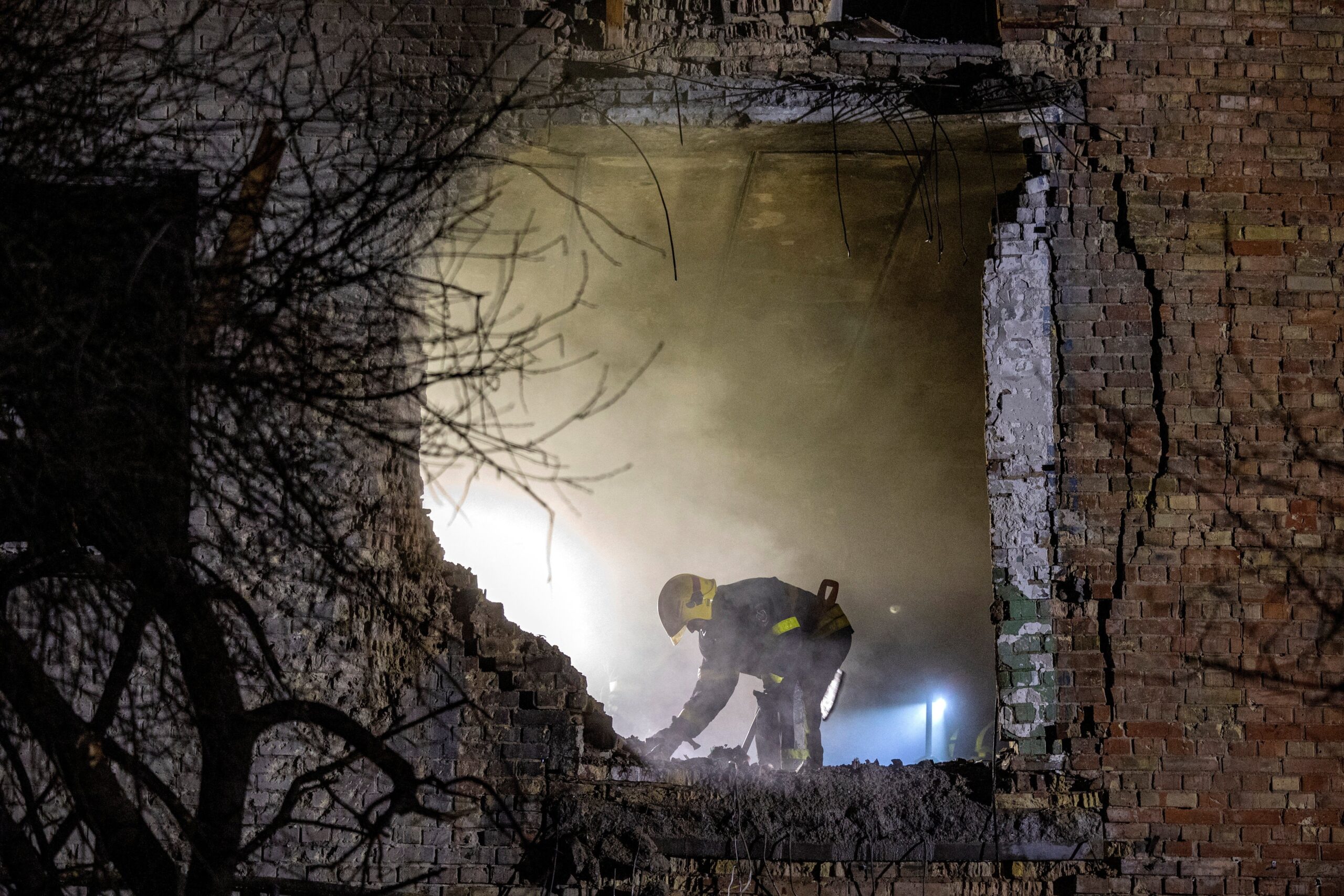 An emergency responder works at the site of an apartment building that was hit during a Russian missile and drone attack on Kyiv