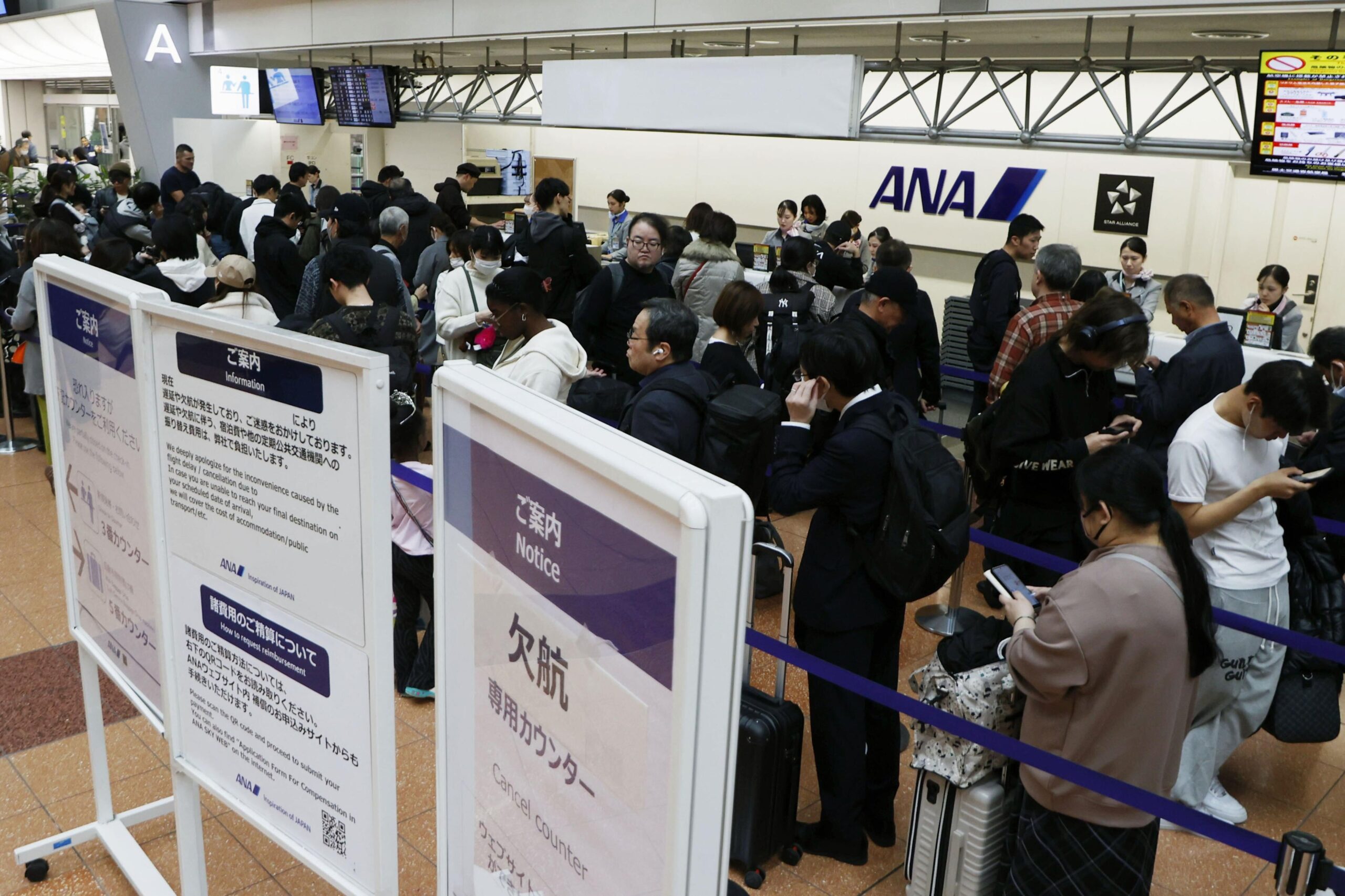 Passengers wait in line at All Nippon Airways' counter at Haneda airport in Tokyo