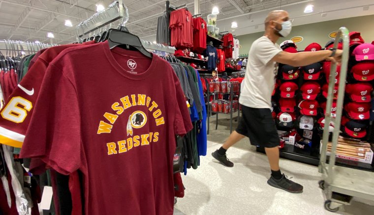 FILE PHOTO: An employee passes Washington Redskins football shirts for sale at a sporting goods store in Bailey's Crossroads, Virginia, U.S., June 24, 2020. REUTERS/Kevin Lamarque/File Photo