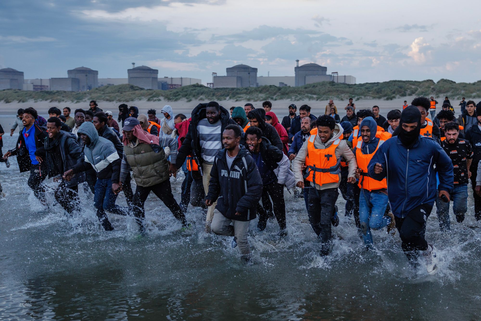 Migrants wade into the water in an attempt to board a small boat on the shoreline in northern France. Unveiling her asylum system reform, Shabana Mahmood said the UK's generosity was a factor that draws people to the UK